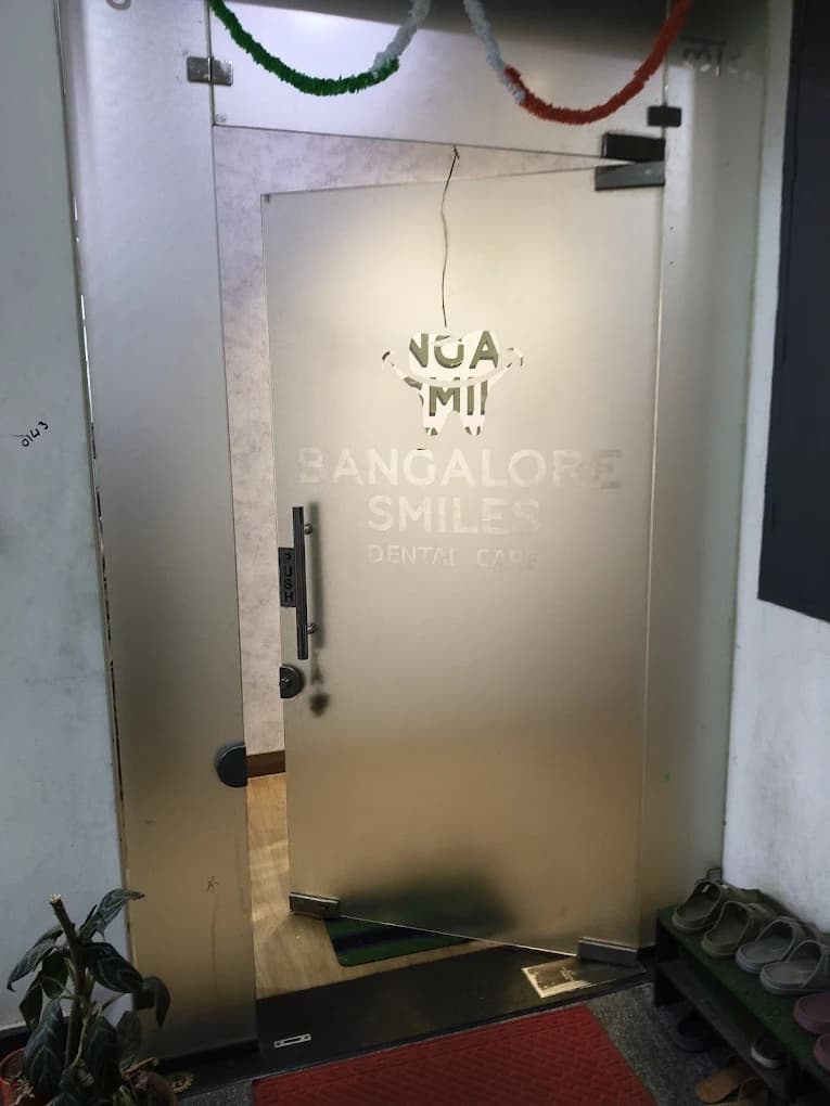 Glass clinic entrance door with frosted Bangalore Smiles Dental Care logo