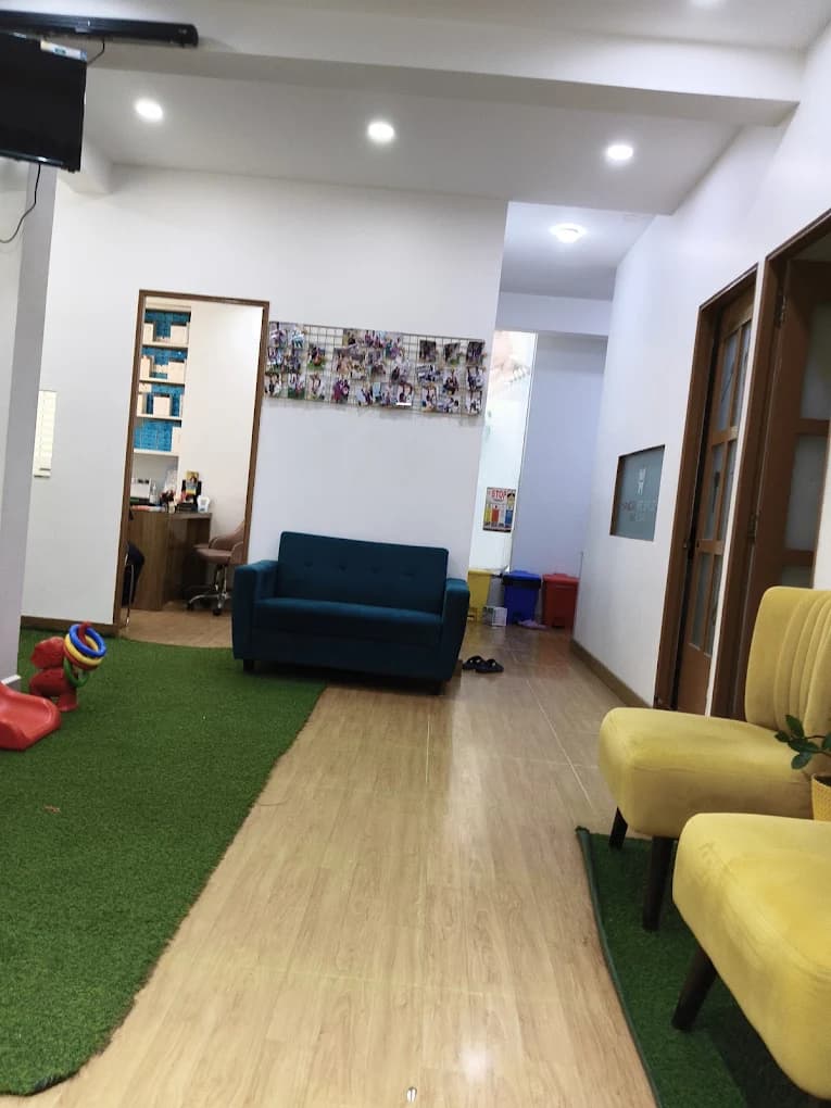 Clinic waiting hallway with blue sofa, children's play mat, toys, and yellow chairs