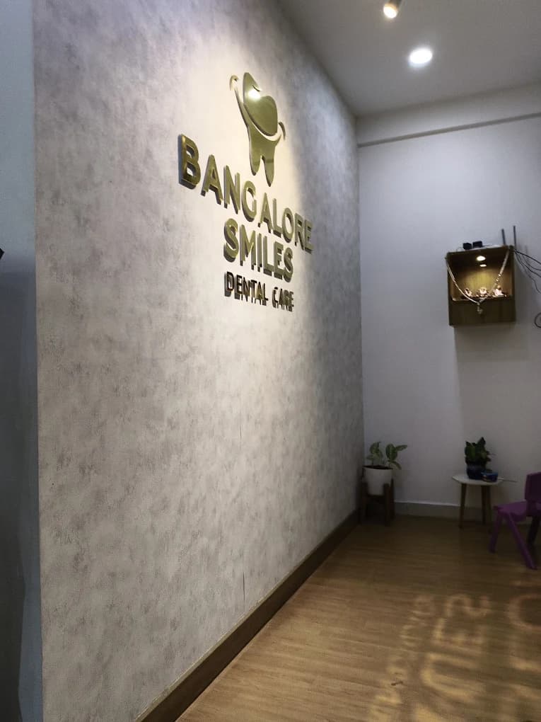 Wall with gold lettering and tooth emblem reading Bangalore Smiles Dental Care