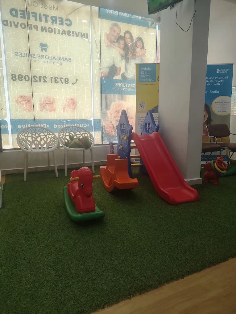 Children's play area with slide and rocking toys on green turf inside Bangalore Smiles