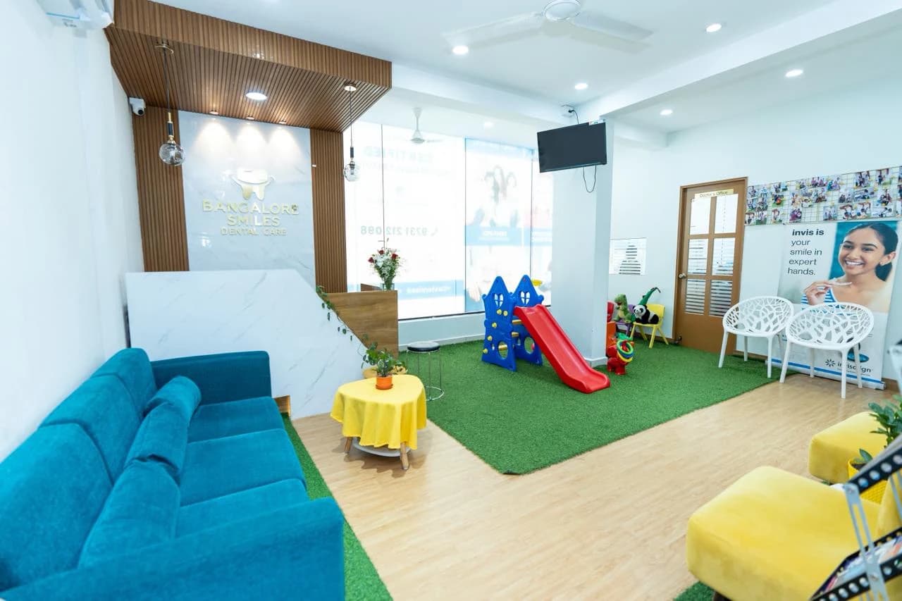 Clinic reception area with blue sofa, yellow table, children's play slide, and consultation room door